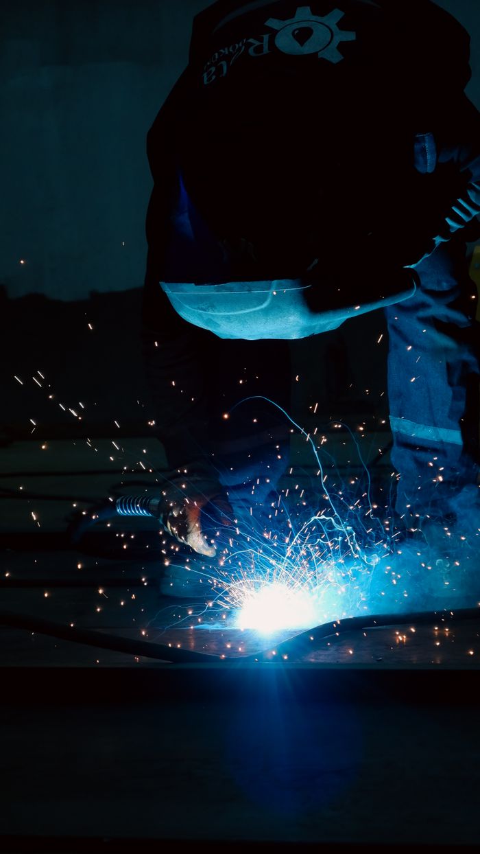 Close-up of a welder in protective gear working with bright sparks flying.